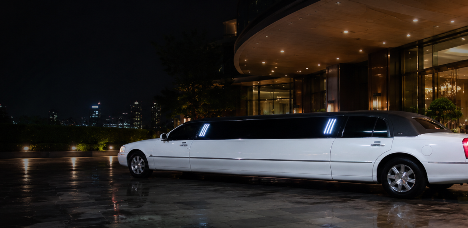 Limousine Lincoln Town Car blanche LIMOSTAR devant un hôtel de luxe la nuit